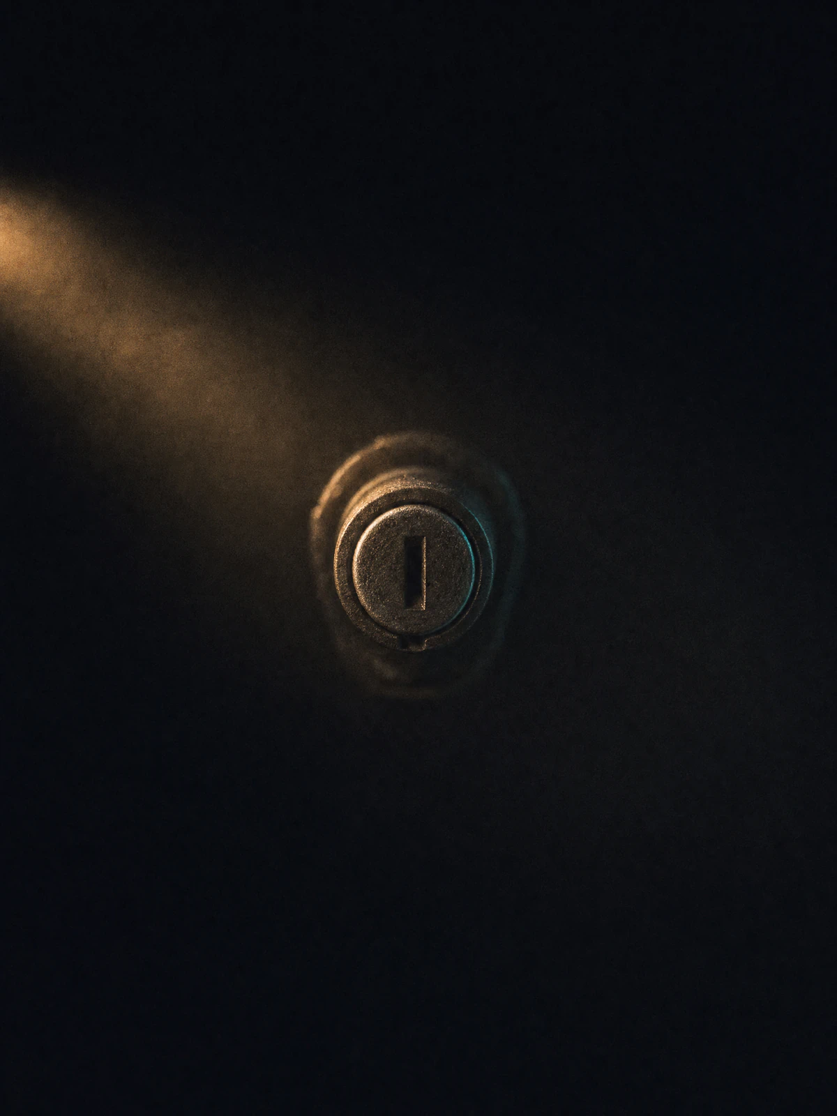 An empty ignition barrel lit by a single warm beam, with no key anywhere.